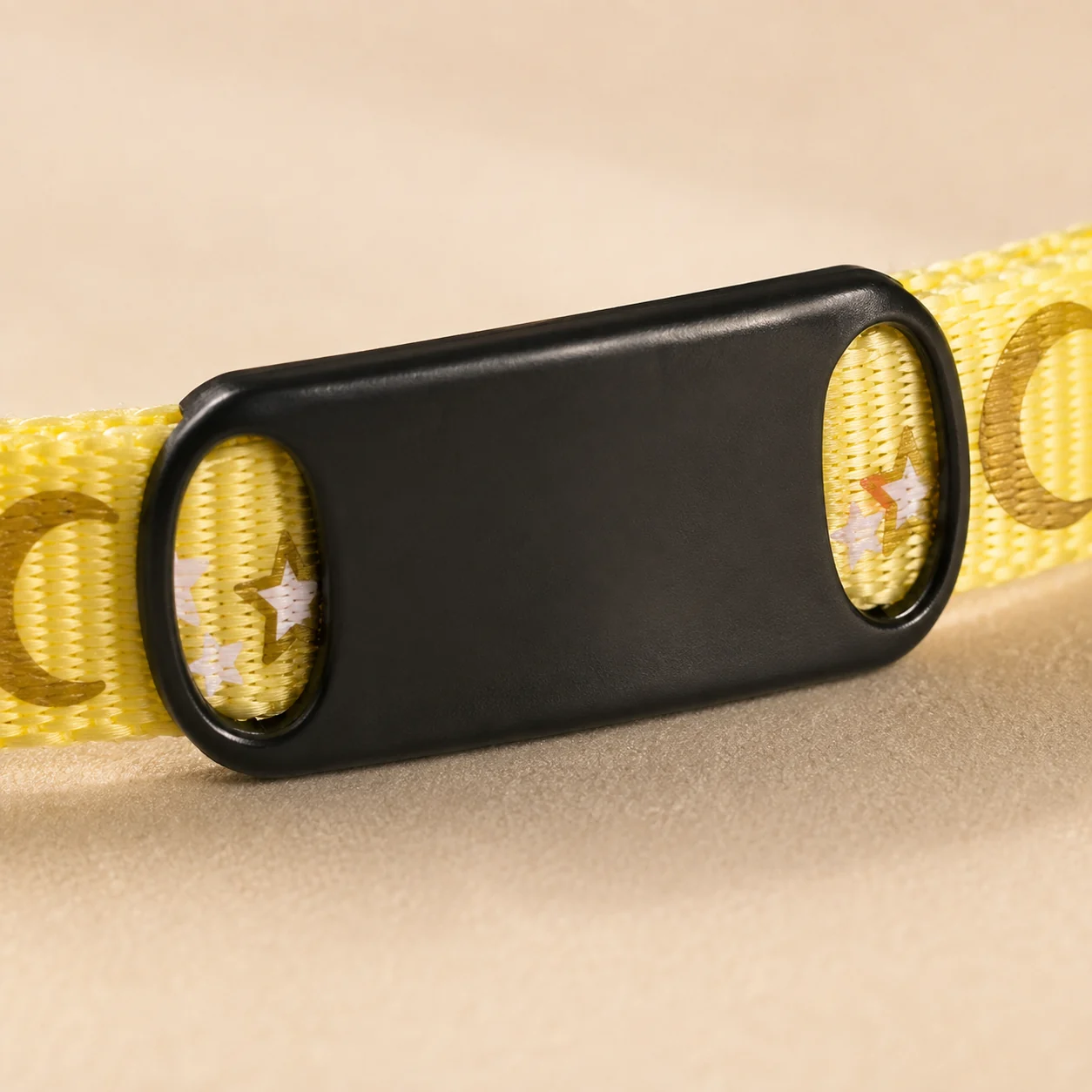 macro de la plaque glissée sur la sangle jaune du collier chat, les deux fentes visibles